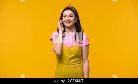 Cheerful woman in wireless earphones isolated on yellow Stock Photo