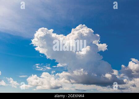 Heart shaped cloud on bright blue sky and white clouds. Stock Photo