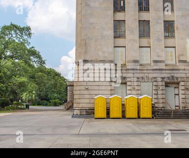 Four yellow portable toilets along side of building Stock Photo