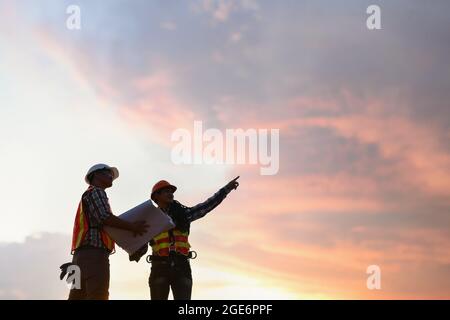 Engineering Consulting People on construction site holding blueprint in his hand. Building inspector. Stock Photo