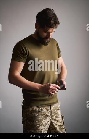 Man Sharpening His Pocket Knife with a Whetstone on a Rustic