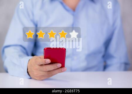 Customer holding phone and pressing star icon for vote score review and feedback with quality and satisfaction, success of digital marketing with resu Stock Photo