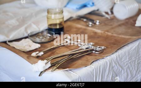 Close up of stainless steel forceps with tampons on brown medical cloth. Set of tools for plastic surgery in operating room. Concept of aesthetic plastic surgery and medical instruments. Stock Photo