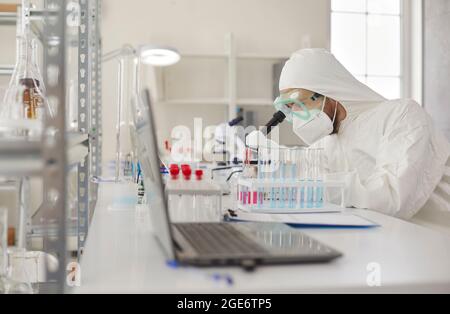 Scientist using microscope, doing research and working on new vaccine in laboratory Stock Photo