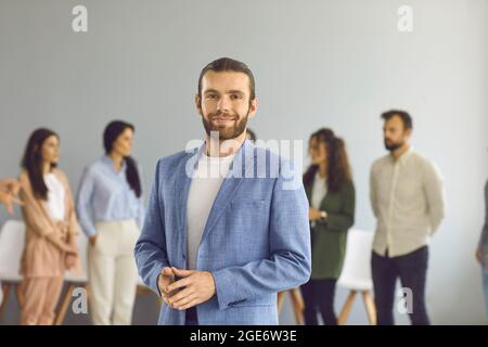 Portrait of a smiling and confident young business man on the background of employees. Stock Photo