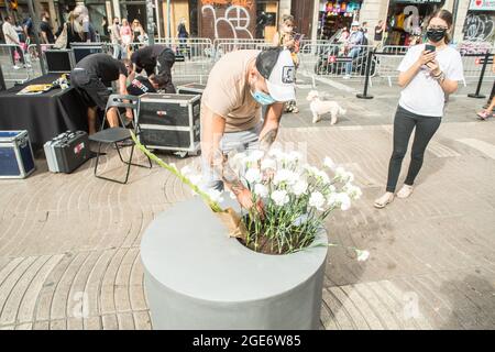 Barcelona, Catalonia, Spain. 17th Aug, 2021. Person is seen depositing flowers to the victims of the Las Ramblas attack in Barcelona.Barcelona pays tribute to the victims on the fourth anniversary of the jihadist attack on La Rambla where on August 17, 2017, a van carried out the massive outrage, which caused the death of 15 people.The families of the victims have been the protagonists of the ceremony, depositing white carnations and bouquets of flowers in three cylinders. This was followed by the authorities, with the mayor of Barcelona, Ada Colau, the president of the Generalitat of Catal Stock Photo