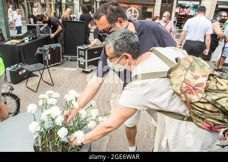 Barcelona, Catalonia, Spain. 17th Aug, 2021. People are seen laying flowers at the victims of the Las Ramblas attack in Barcelona.Barcelona pays tribute to the victims on the fourth anniversary of the jihadist attack on La Rambla where on August 17, 2017, a van carried out the massive outrage, which caused the death of 15 people.The families of the victims have been the protagonists of the ceremony, depositing white carnations and bouquets of flowers in three cylinders. This was followed by the authorities, with the mayor of Barcelona, Ada Colau, the president of the Generalitat of Cataloni Stock Photo