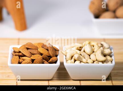 Mix of Nuts, Almond, Cashew, Wallnut in white ceramic bowls on wooden stand, Healthy snack food, Diet food Stock Photo