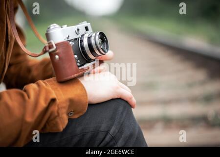 Photographer in brown jacket taking in hands retro camera closeup Stock Photo