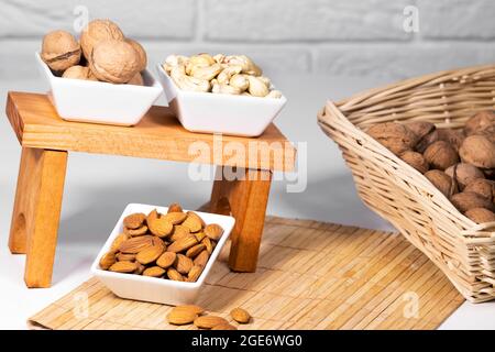 Mix of Nuts, Almond, Cashew, Wallnut in white ceramic bowls on wooden stand, Healthy snack food, Diet food Stock Photo