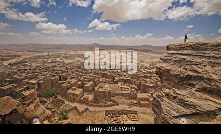 Man standing and watching  one of the oldest cities in Yemen Thula city Stock Photo