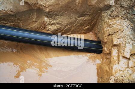 Repair of the underground pipeline. Laying a plastic pipe underground by tightening. Stock Photo