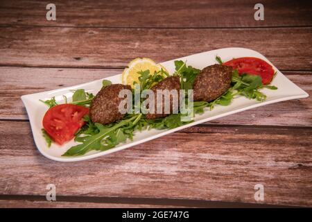 Traditional kebbe and pita bread on big round plate in lebanese restaurant Stock Photo