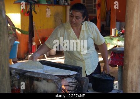 tortillas de maíz azul cociendose en comal de barro Stock Photo