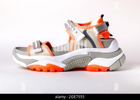 Women's, fashionable, sports sandals with orange accents on a white background. New youth shoes for girls. Side view Stock Photo