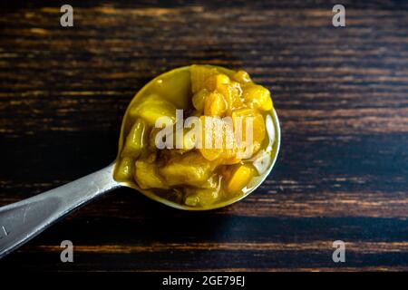 Tablespoon of Canned Hatch Green Peppers: A measuring spoon filled with diced green New Mexico chili peppers Stock Photo