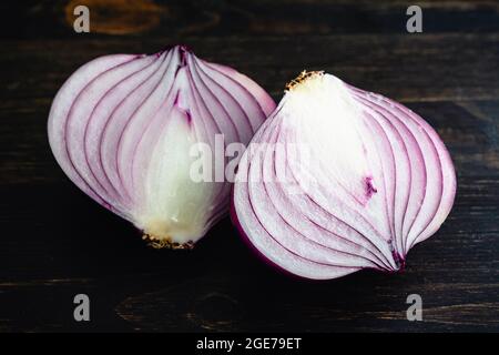 Peeled and Halved Red Onion on a Dark Wood Table: Two pieces of peeled red onion on a wooden table or cutting board Stock Photo