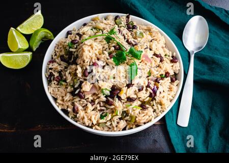 Cilantro Lime Rice with Black Beans in a Serving Bowl: A bowl of beans and rice garnished with cilantro and shown with a serving spoon Stock Photo