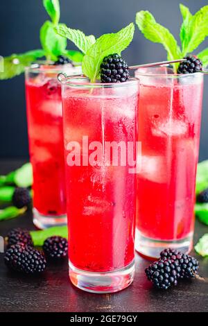Blackberry Mojito Cocktails Served in Tall Glasses: Mojitos made with mint, blackberries, and rum and served over ice with garnishes Stock Photo