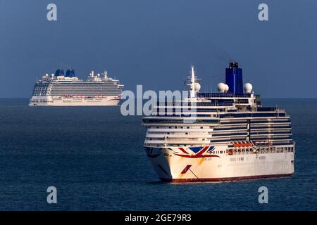 The huge Britannia cruise ship (left) sails away behind Arcadia in waters off the coast of Torbay, Devon, UK. Stock Photo