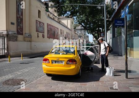 Cordoba, Argentina - January, 2020: Man gets into taxi on Bernardino Rivadavia street near church called Basilica Nuestra Senora de La Merced at inter Stock Photo