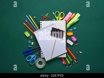 School supplies and black table lamp on green board. Concept back to school. Mock up for design. Copy space. Education Concept. Stock Photo