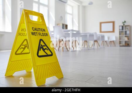 Yellow sign with the inscription Caution Wet Floor which was put in the office after cleaning. Stock Photo