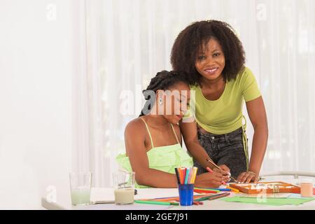 Afro American teachers helping small student with her drawings Stock Photo