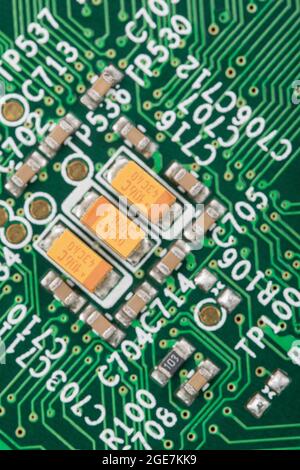 Rare earth Tantalum oxide surface mount / SM capacitors on bright green pcb + lots of interconnecting wires & component through-holes. No brand ID Stock Photo