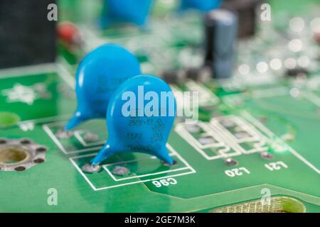 Close shot of blue coloured ceramic disk capacitors on a green pcb. For leaded capacitor, small electronic components. Capacitor maker not known. Stock Photo