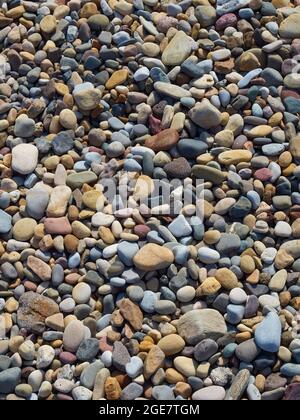 A full frame of many, many pebbles and rocks deposited on a beach and forming an abstract near-mosaic under the influence of the sea and tide. Stock Photo