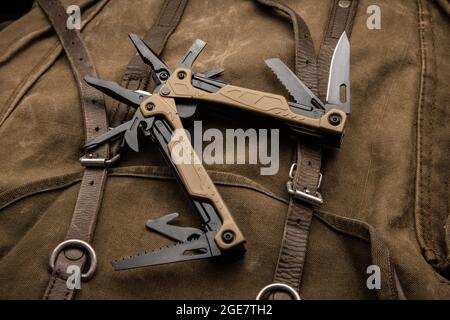 Modern multitool with many tools. A portable multitasking tool on a vintage canvas backpack. Stock Photo