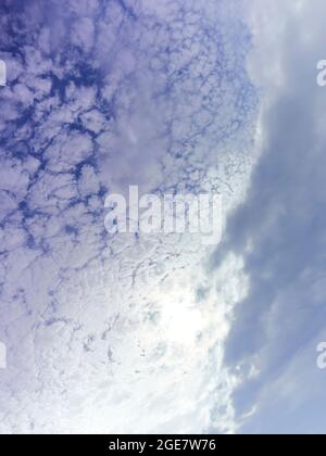 Abstract view of cloud fronts clashing overhead, fragmenting and coalescing like icebergs breaking off from a glacier, against a deep blue sky. Stock Photo