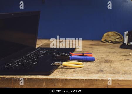 Laptop and tools on a wooden table - repairing a laptop Stock Photo