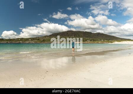 Traveler woman with her feet in clear turquoise water at Dog's Bay, Galway, Ireland Stock Photo
