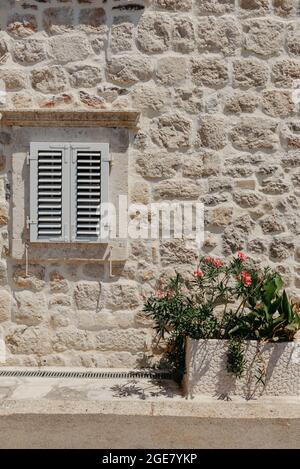 Old window with wooden shutters on yellow stucco wall and copy space Old Shutter windows with a flowers. Montenegro. Mediterranean. Stock Photo