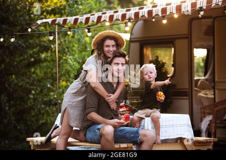 Parents recreating with child outside camper on road trip. Young family enjoy vacation in trailer Stock Photo