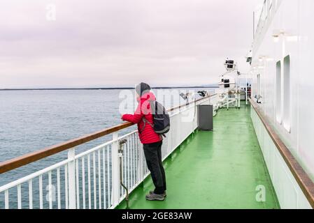 Woman on the deck of a passenger ferry in navigation on a cloudy summer evening Stock Photo