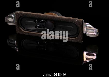 Speaker from a multimedia device on a dark base. Spare parts for TV repair. Dark background. Stock Photo