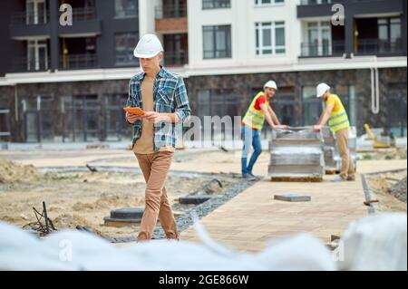 Serious focused construction engineer looking at his gadget Stock Photo