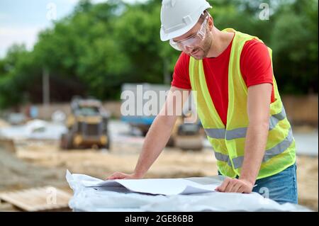 Worker in protective eyewear leaning over a technical drawing Stock Photo