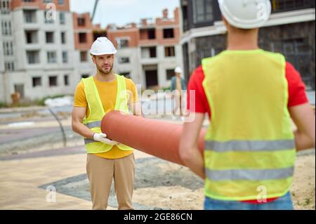 Two construction workers in reflective waistcoats and hardhats working outdoors Stock Photo