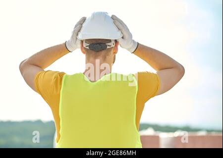 Builder covering his head with a protective helmet before work Stock Photo