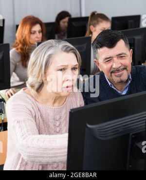 Middle aged man explaining computer skills for mature woman Stock Photo