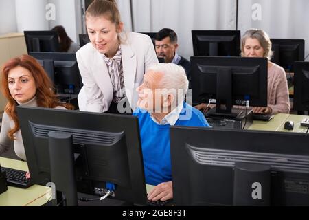 Serious business woman helping to male partner, pointing at computer monitor Stock Photo