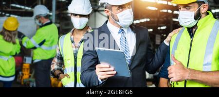 Diversity factory worker working with tablet, Industrial Engineer in the hard hat uses  small computer while standing in the heavy industry manufactur Stock Photo