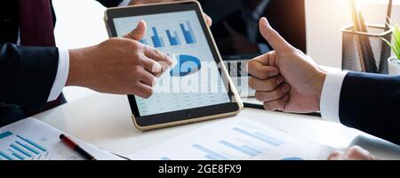 Cropped shot of a group of businesspeople looking at graphs on digital tablets, Analyzing electronic document, Discussing plan and idea to improvement Stock Photo