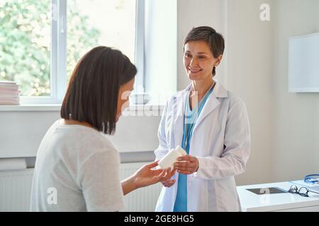 Friendly mature woman doctor prescribing medicine to smiling african american female patient Stock Photo