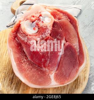 Raw ham leg on ligth gray background. Organic gourmet food concept. Stock Photo