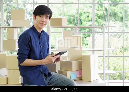 Young entrepreneur checking products stock with tablet computer at home office. Work from home concept. Stock Photo